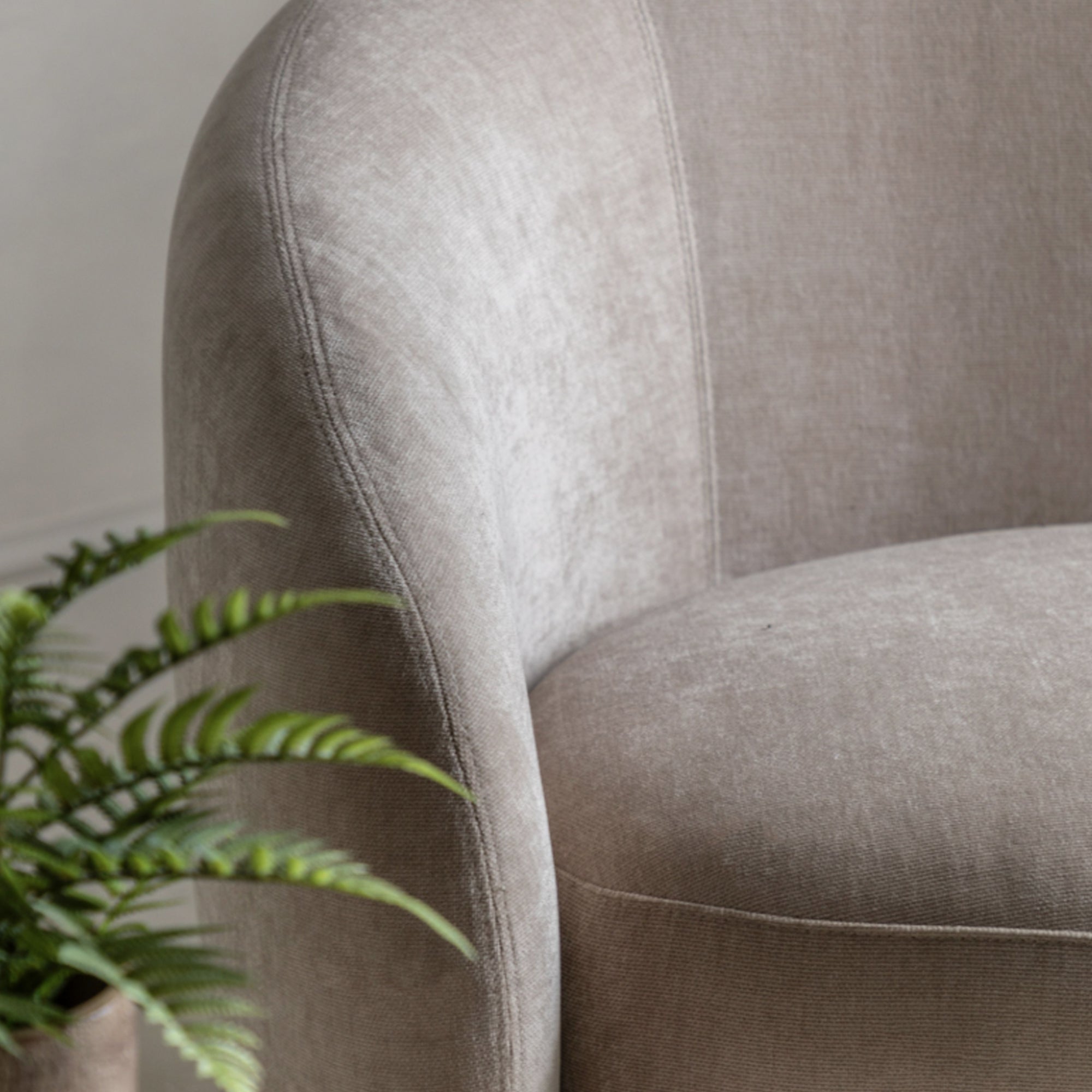 Close-up of a textured cream armchair with a plant in the foreground