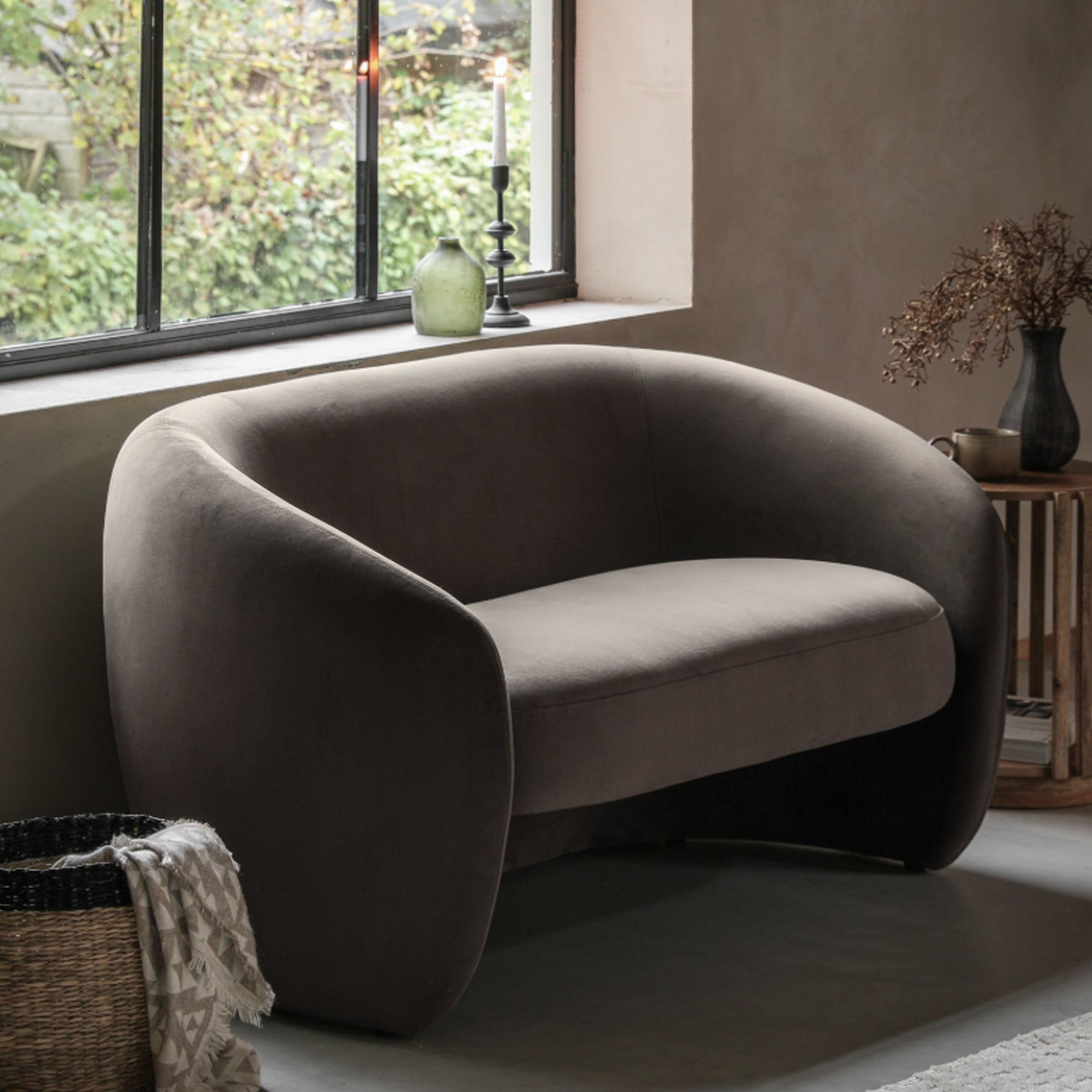 Gray armchair in a room with a window and decorative items.