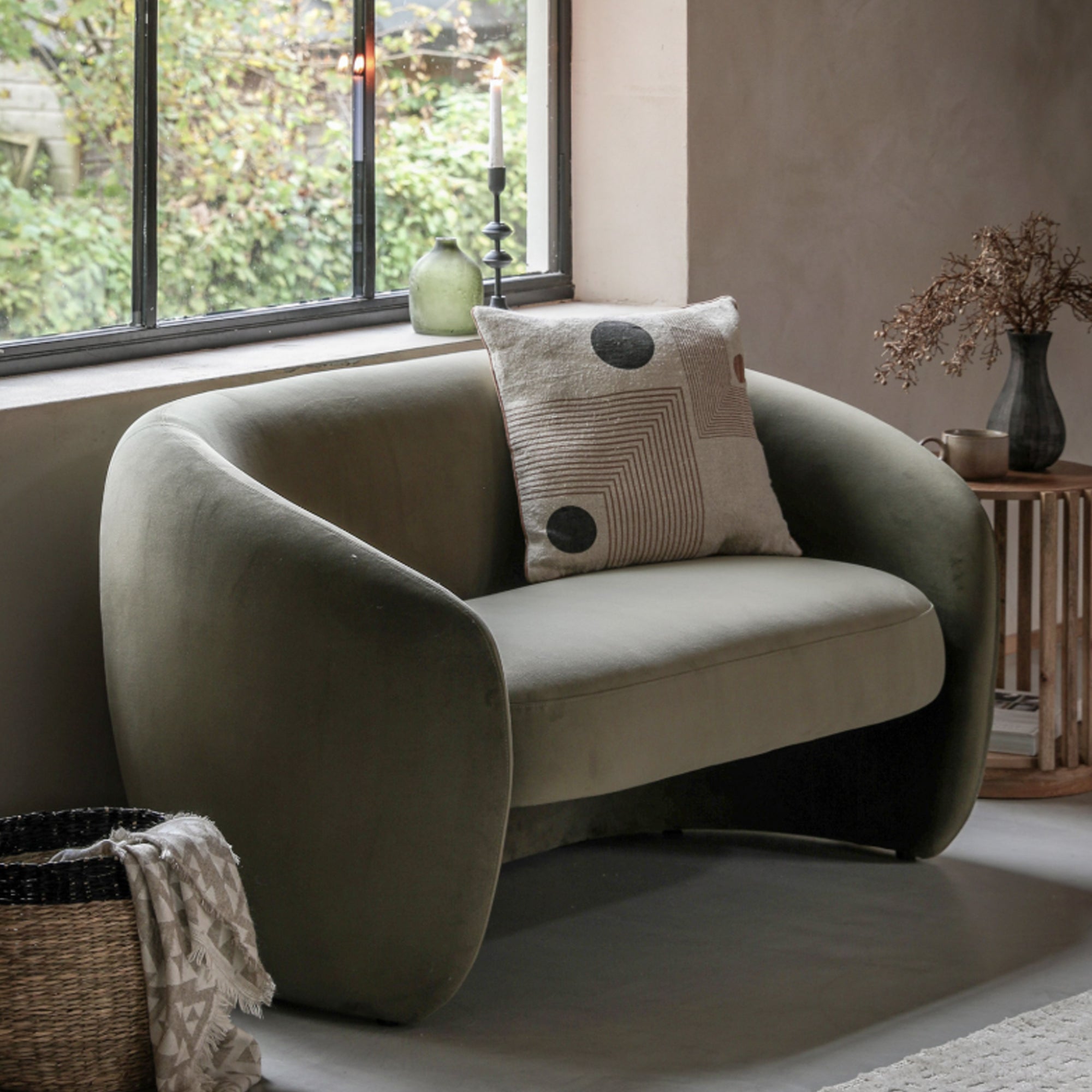 Green armchair with a cushion in a room with a window and decorative elements.