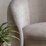 Close-up of a textured cream armchair with a plant in the foreground