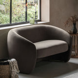 Gray armchair in a room with a window and decorative items.