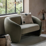 Green armchair with a cushion in a room with a window and decorative elements.